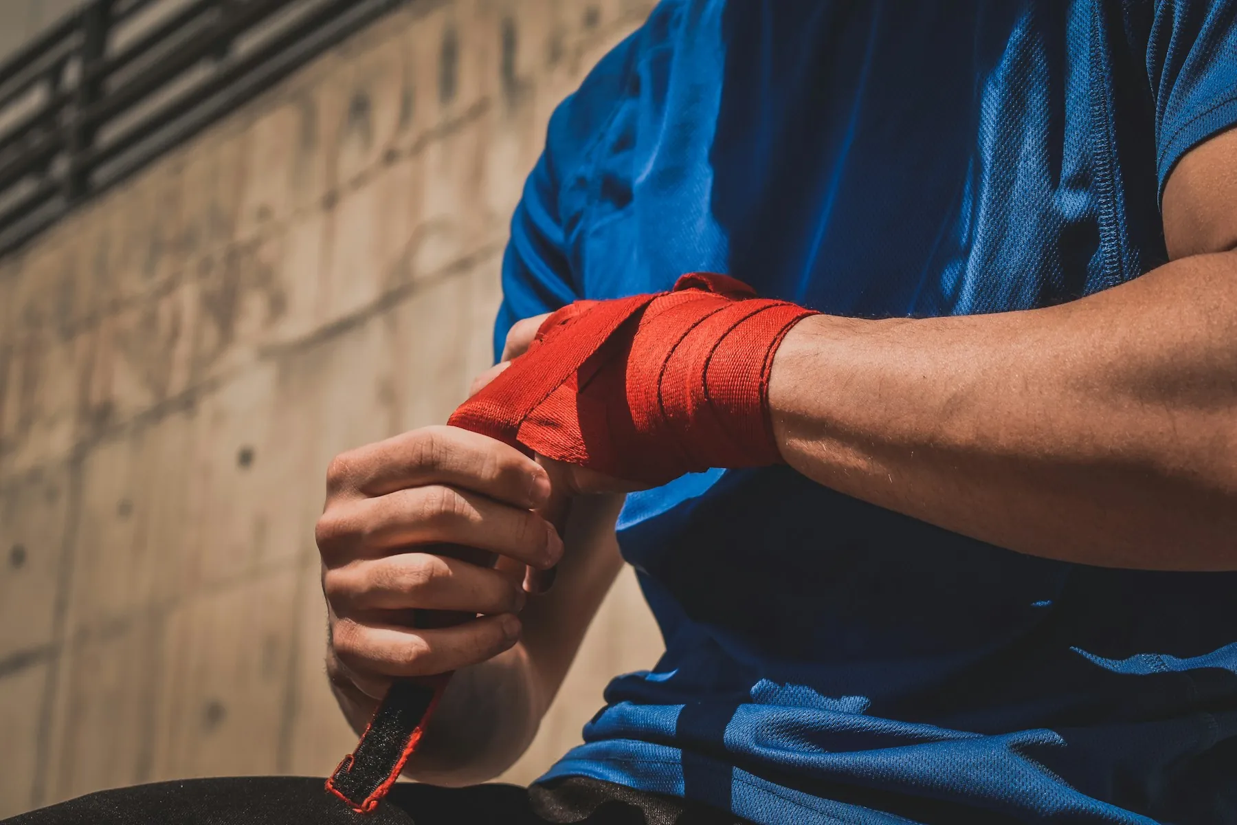 Athlete wrapping hands with red boxing wraps